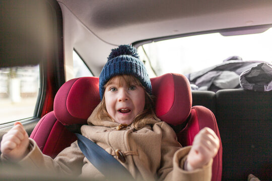 Excited little girl sitting in car seat during road trip. Authentic joy and excitement during family travel. Road safety, childhood wonder, thrill of adventure, family vacations, travel lifestyle.