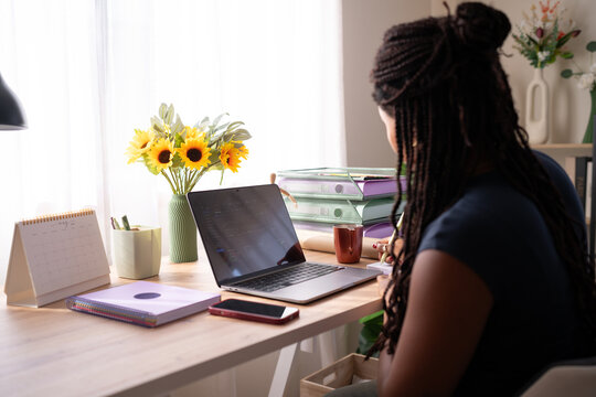 African American woman works from her home office desk with a laptop