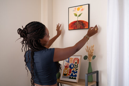 African American woman hanging her painting on the wall