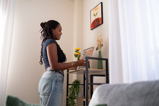 African American woman decorates a shelf with her own artwork