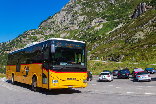 Yellow Swiss PostBus transit vehicle driving at Susten pass, Switzerland