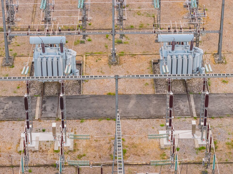 Aerial view of two high voltage power transformers and electrical switching equipment inside a power distribution substation in Valence, Auvergne-Rhone-Alpes, France.