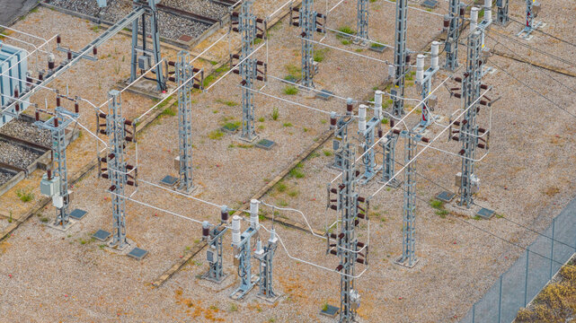 Aerial view of high voltage electrical substation equipment with busbars, insulators and switching infrastructure for power transmission in Valence, Auvergne-Rhone-Alpes, France.