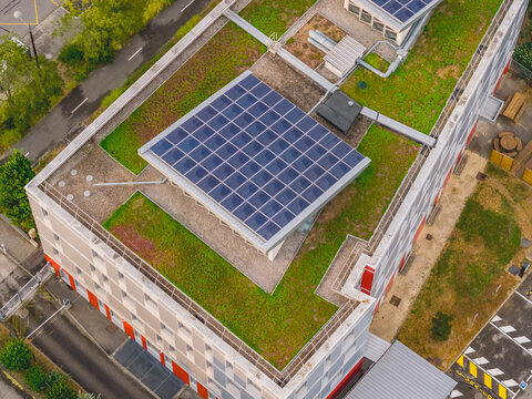 Aerial view of photovoltaic solar panels installed on a green roof, combining renewable energy, sustainable architecture and urban vegetation in Valence, Auvergne-Rhone-Alpes, France.