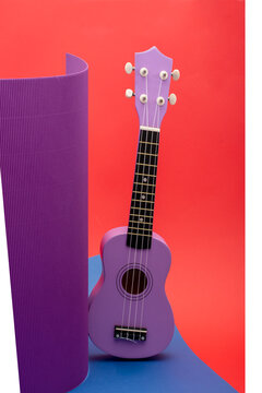 Four-string ukulele guitar on a colored background