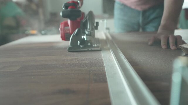 Red circular saw positioned on a metal guide rail ready to cut a walnut countertop