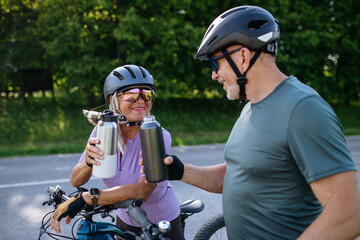 Naklejka premium Mature couple resting and drinking water on bike tour.