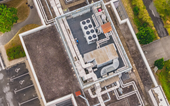 Aerial view of complex rooftop HVAC infrastructure with cooling units, ventilation ducts and utility systems on a modern industrial building in Valence, Auvergne-Rhone-Alpes, France.