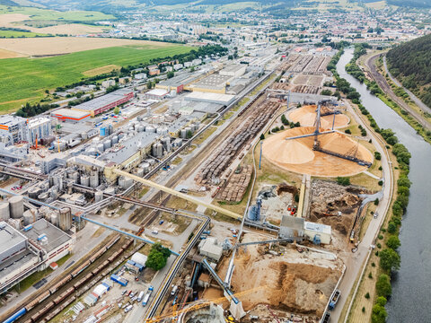 Aerial view of Mondi SCP factory with extensive wood storage piles, industrial buildings, railway tracks, and a river in Ruzomberok, Zilinsky kraj, Slovakia.