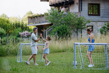 Obraz premium Family playing soccer together in backyard during summer.