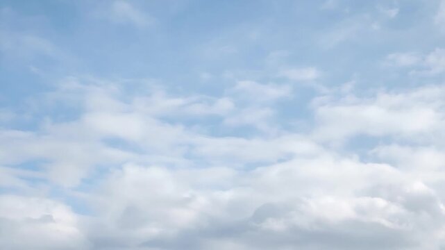 White clouds moving across a beautiful serene light blue sky during a sunny summer day, showcasing a natural skyscape background