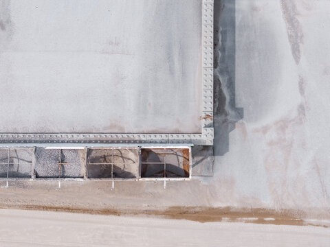 Aerial view of a construction site featuring concrete retaining walls and partitioned storage bays filled with gravel and sand in Latvia.