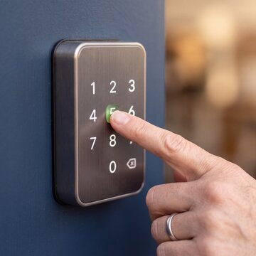 Close-up of fingertip pressing smart door lock keypad