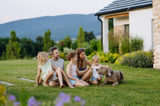 Parents and daughters enjoying late summer together outside family home.