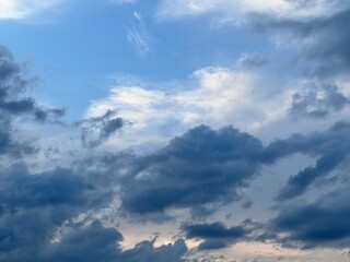 Fototapeta premium Dramatic blue sky with dark storm clouds and soft sunlight breaking through cloudy summer atmosphere