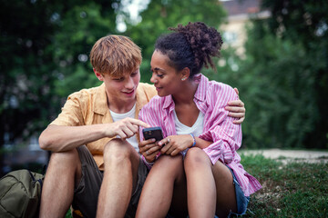 Young couple checking smartphone during walk in park.
