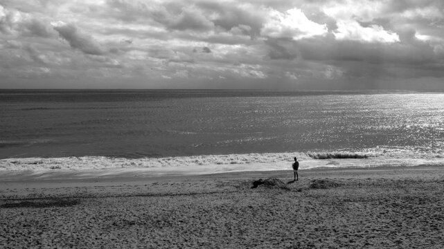 Solitary Figure Beneath an Overcast Sky on a Wide, Empty Beach