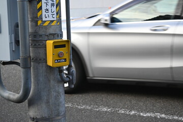 Fototapeta premium 押しボタンの前を通り過ぎるシルバーの自動車