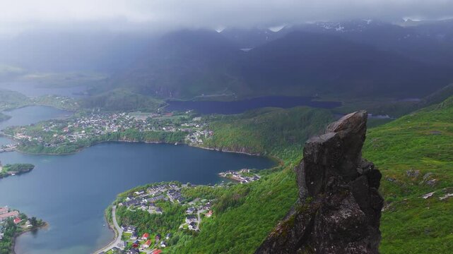 Aerial drone shot of Svolvaergeita rock pinnacle on mount Floya above Svolvaer town surrounded by fjords and mountains in Lofoten, Norway.