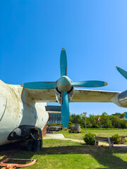Airplane propeller in a park under a clear blue sky with surrounding greenery and buildings in the background © DSMT