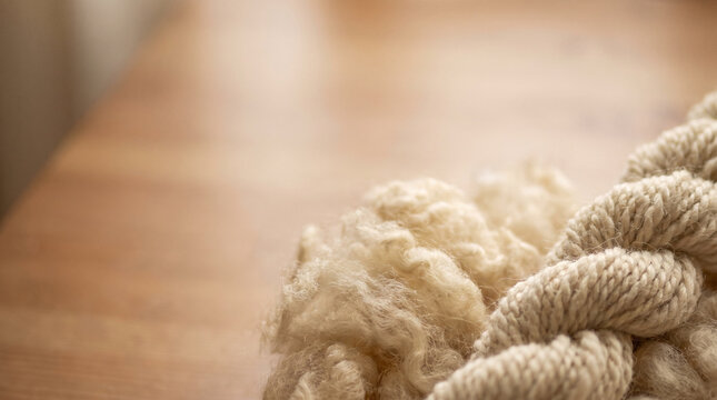 Soft raw wool and twisted handspun yarn on a wooden table  