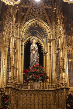 Statue of the Virgin Mary displayed within an ornate Gothic altar inside a historic cathedral. Intricate gold architectural details, religious symbolism and sacred Christian heritage create.