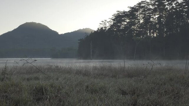 Aerial sunrise view of Tuyen Lam Lake in Da Lat, Lam Dong, Vietnam, with Pinhatt Mountain, pine forests and drifting mist and clouds creating a serene Central Highlands landscape. ( Suoi Tia )