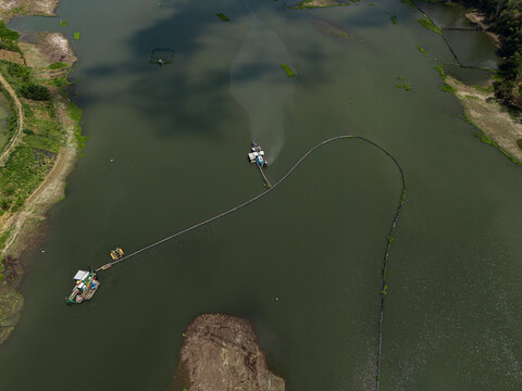 Aerial view of a specialized suction dredger and a floating platform deployed to extract sediment and debris from the bed of the Sengguruh Reservoir in Malang, East Java, Indonesia.