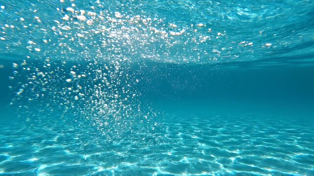 Bubbles rising through clear turquoise water with sandy seabed during daytime