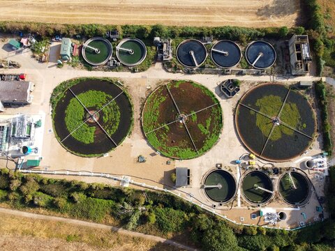 Aerial view of Raunds Water Recycling Centre with circular sedimentation tanks and filtration systems surrounded by green vegetation in Raunds, England, United Kingdom.
