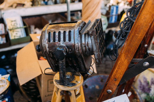Close up of a retro industrial metal spotlight or theater lantern displayed at an antique market stall. Concept of vintage lighting, film equipment, retro decor, and stage.