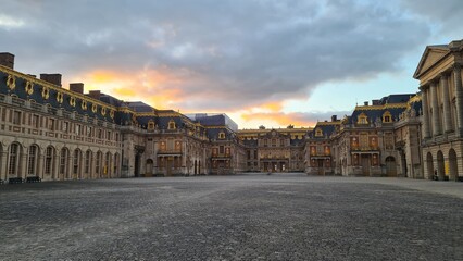 Obraz premium La Cour royale du château de Versailles vue depuis le Grand Portail au coucher du soleil (France)