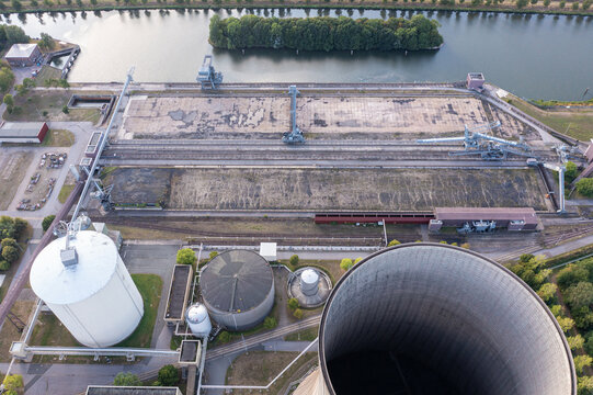 Aerial view of decommissioned Kraftwerk Heyden in Lahde, featuring empty coal storage yard, industrial silos, and cooling tower in Petershagen, North Rhine-Westphalia, Germany.