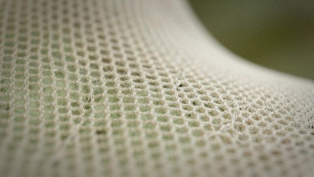 Macro close-up of a structured white mesh or technical fabric with hexagonal pattern