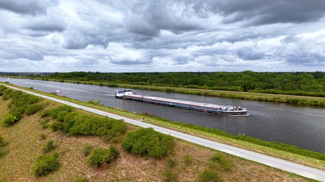 Cargo barge navigates Mittellandkanal in Germany under dramatic cloudy sky, representing inland freight transport. European waterway links major logistics routes toward Netherlands and Poland
