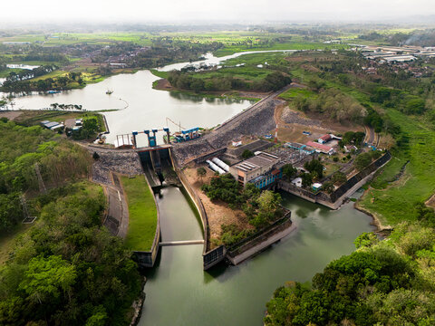 Aerial view of PLTA Sengguruh hydroelectric power plant with its dam structure, reservoir, and surrounding lush greenery in Malang, East Java, Indonesia.
