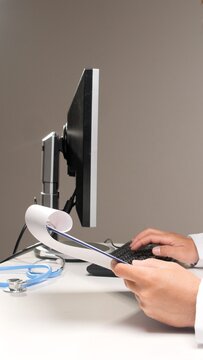 Medical professional typing patient data on a keyboard while holding a clipboard, illustrating digital record keeping, clinical administration, and modern healthcare documentation processes