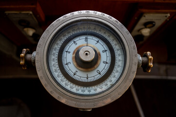 Top view of vintage nautical gyrocompass navigation repeater with round degree scale dial and metal adjustment knobs in ship bridge wheelhouse. © Marina