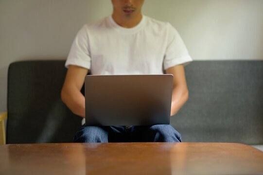 Casual Young Man Working on Laptop in Cozy Indoor Setting