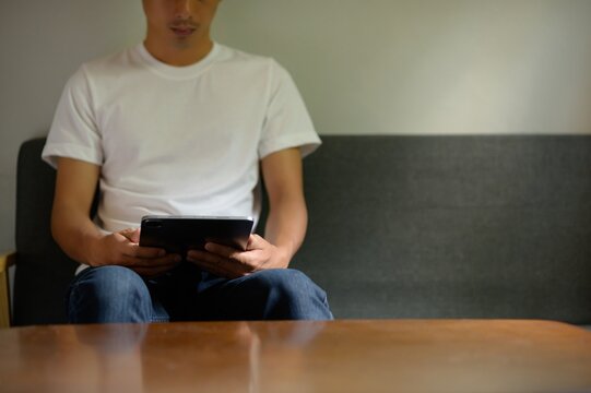 Person Sitting on Sofa Using Tablet Device in Indoor Setting