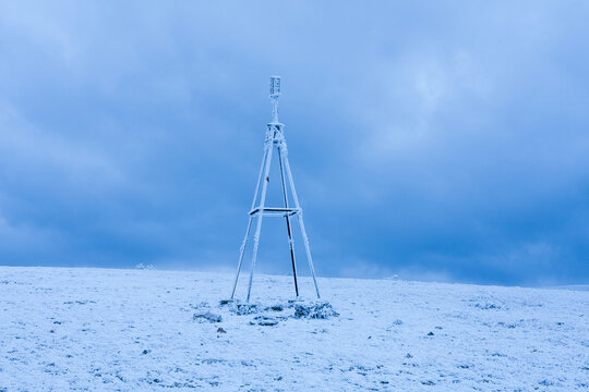 Icy triangulation tower stands alone on a snow-covered mountain peak