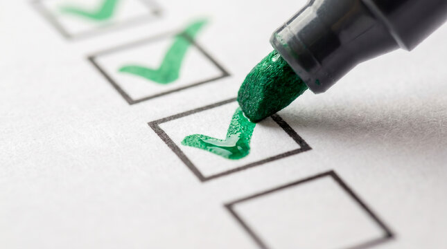 Green felt tip marker checking boxes on a checklist with green check marks macro close up