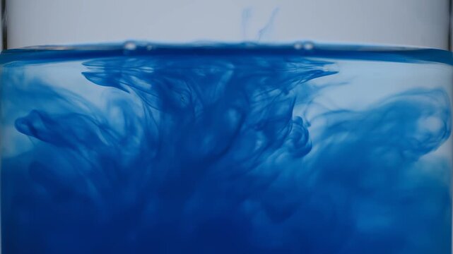 Dark blue ink dissolving in clear water with gentle motion during close-up macro shot