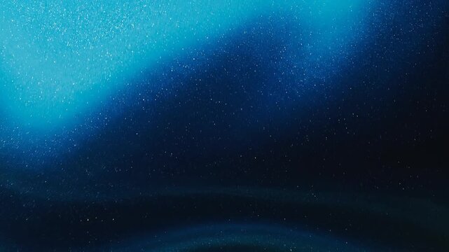 Deep blue ink spreading in water with soft light illuminating fluid motion for abstract backgrounds