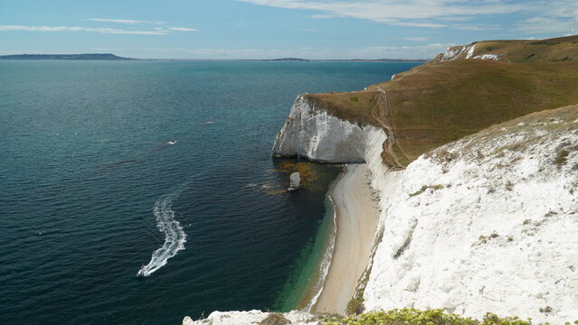 Speedboat leaving wake near chalk cliffs at Bats Head Dorset England