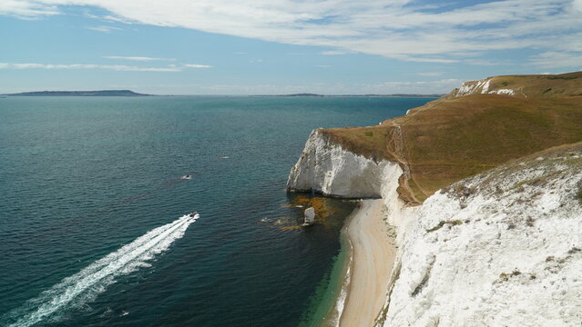 Speedboat creating long white wake trail by Bats Head cliffs Dorset England