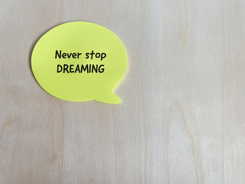 Yellow speech bubble displaying &ldquo;Never Stop Dreaming,&rdquo; symbolizing ambition, motivation, hope, personal goals and positive thinking.