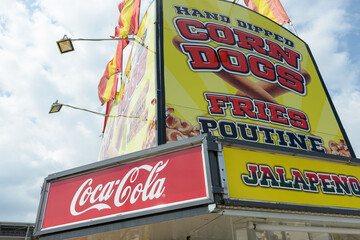 Obraz premium multi-item midway concession stand signs featuring Coca-Cola, hand-dipped corn dogs, fries, poutine, and jalapeño-spiced items at the CNE, Exhibition Place, Toronto (22 August 2026)