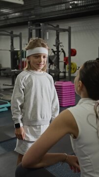 Vertical video of child high-fiving female trainer and doing warm up exercise in gym. Clip is perfect for promoting youth sports programs and healthy lifestyle habits for kids