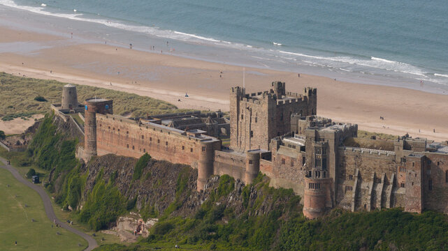 Aerial view of Bamburgh Castle perched on a rocky outcrop overlooking the sandy beach and the North Sea in Bamburgh, England, United Kingdom.